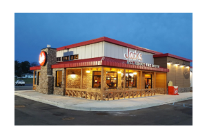 Jack’s restaurant exterior with a red roof, illuminated windows, outdoor seating and a front porch area at dusk.