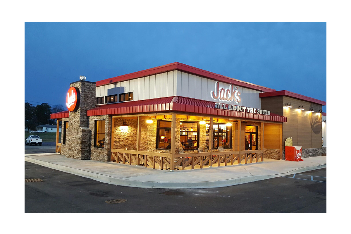 Jack’s restaurant exterior with a red roof, illuminated windows, outdoor seating and a front porch area at dusk.