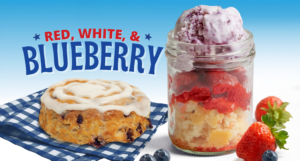 A blueberry biscuit with white icing sits on a blue gingham napkin beside a mason jar layered with fruit and blueberry dessert, strawberries, and blueberries. Text reads “Red, White, & Blueberry.”